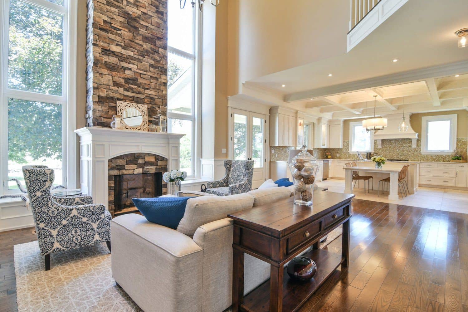 Two-storey great room with floor-to-ceiling stone fireplace and coffered ceiling in a Creek Road custom home