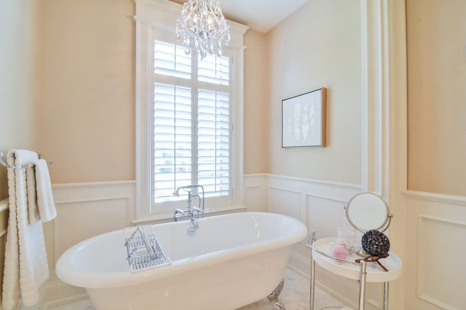 Primary ensuite with freestanding tub, wainscoting and chandelier in a Creek Road custom home