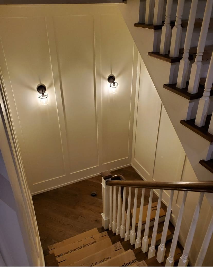 Stair hall with panelled wainscoting and brass sconce lighting